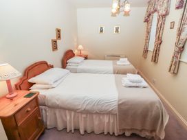 A bedroom with two single beds bedside tables lamps and framed pictures on the walls at Periwinkle Akeld near Wooler