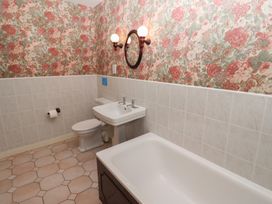 A bathroom with a bathtub a sink a toilet and floral wallpaper at Periwinkle in Akeld near Wooler