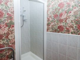 A small shower cubicle with tiled walls and a floral wallpapered bathroom wall at Periwinkle Akeld near Wooler