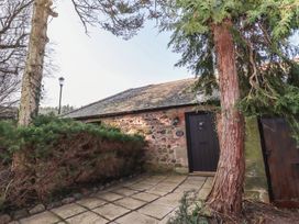 A stone cottage with a dark door and shrubs in front at Lavender cottage in Akeld near Wooler