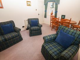 A sitting room with plaid armchairs and a wooden dining table with chairs at Lavender cottage Akeld near Wooler