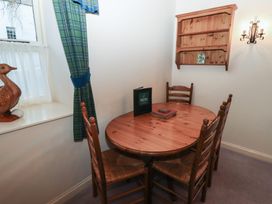 A dining area with a wooden table and four chairs near a window with green curtains at Lavender cottage Akeld near Wooler