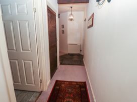 A narrow hallway with a red patterned rug a white door open on the left and a wooden louvered door on the right at Lavender cottage Akeld near Wooler