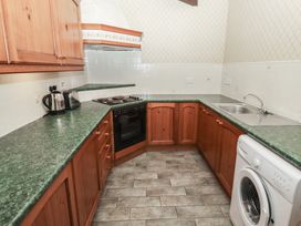 A kitchen with wooden cabinets green countertops a stove oven a sink a washing machine and small appliances at Lavender cottage Akeld near Wooler