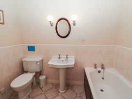 A bathroom with a toilet sink and bathtub with two wall lights and an oval mirror at Lavender cottage Akeld near Wooler