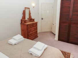 A bedroom with a bed that has folded towels on it a wooden dresser with a mirror a white door and wooden wardrobe doors at Lavender cottage in Akeld near Wooler