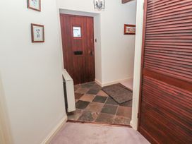 A hallway with a wooden door tile flooring a carpeted floor and framed pictures on the walls at Lavender cottage Akeld near Wooler