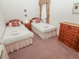 A bedroom with two single beds bedside table dresser and window with floral curtains at Lavender cottage Akeld near Wooler