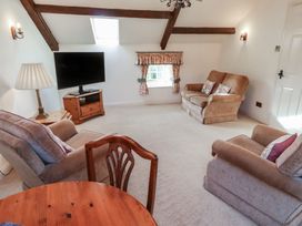 A living room with armchairs a wooden chair a table a television and a window with floral curtains at Freesia Cottage Akeld near Wooler