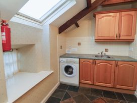 A kitchen area with wooden cabinets a washing machine a sink a skylight and a fire extinguisher at Freesia Cottage Akeld near Wooler