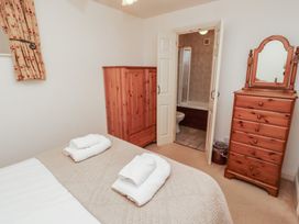 A bedroom with a bed covered with folded white towels wooden wardrobe wooden chest of drawers and an open door to a bathroom at Freesia Cottage Akeld near Wooler