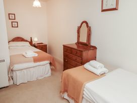 A bedroom with two single beds wooden furniture and folded towels at Freesia Cottage Akeld near Wooler
