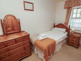 A bedroom with a single bed a wooden dresser with mirror and a wooden bedside table at Freesia Cottage Akeld near Wooler