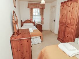 A bedroom with two single beds wooden furniture and a window with patterned curtains at Freesia Cottage Akeld near Wooler
