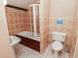 A bathroom with a bathtub and shower, a toilet, and a sink at Freesia Cottage Akeld near Wooler