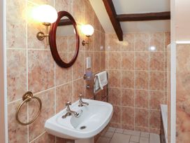 A bathroom with a white sink mirror wall lights towel ring and a towel rail at Freesia Cottage in Akeld near Wooler