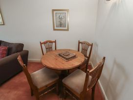A dining area with a round wooden table and four wooden chairs with cushions and framed picture on the wall at Aubretia Trail in Akeld near Wooler
