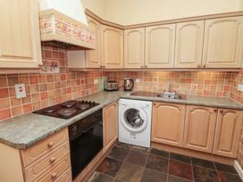 A kitchen with wooden cabinets a washing machine an oven stove kettle and toaster at Aubretia Trail in Akeld near Wooler