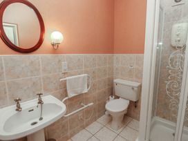 A bathroom with a sink a round mirror a toilet and a shower at Aubretia Trail Akeld near Wooler