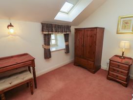 A small room with a wooden wardrobe desk and side table with lamp at Aubretia Trail Akeld near Wooler