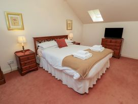 A bedroom with a double bed towels on blanket bedside tables lamps a dresser with television and skylight at Aubretia Trail in Akeld near Wooler