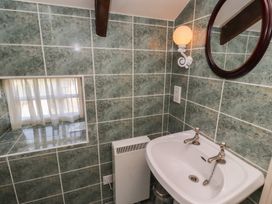 A bathroom corner with a sink mirror and wall light at Aubretia Trail in Akeld near Wooler