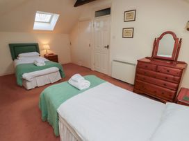 A bedroom with two single beds green throws wooden dresser with mirror and skylight at Aubretia Trail in Akeld near Wooler