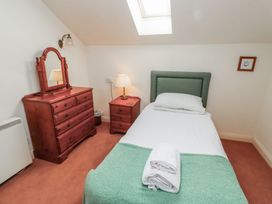 A bedroom with a single bed a dresser with mirror a bedside table and a skylight at Aubretia Trail in Akeld near Wooler