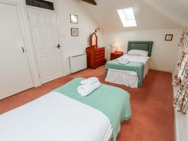 A bedroom with two single beds green blankets and white towels a dresser with mirror and a skylight at Aubretia Trail Akeld near Wooler