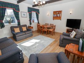 A living room with couches a dining table a television and windows with curtains at Bizzie Lizzie Akeld near Wooler