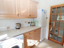 A kitchen countertop with a kettle, toaster, glass cutting board and a fridge beside a door at Bizzie Lizzie in Akeld near Wooler