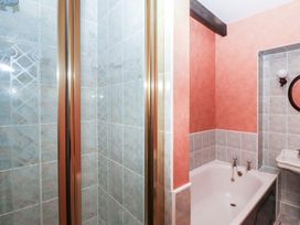 A bathroom with a bathtub shower enclosure and a sink at Bizzie Lizzie Akeld near Wooler