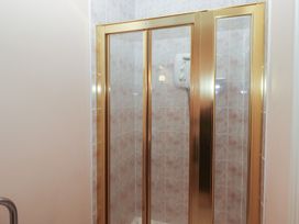 A shower stall with a brass frame and tiled walls at Bizzie Lizzie Akeld near Wooler