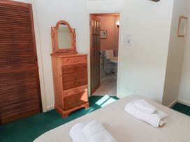 A bedroom with a wooden chest of drawers a mirror towels on a bed and a bathroom visible at Bizzie Lizzie Akeld near Wooler