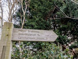 A wooden public bridleway sign among trees and bushes at Bizzie Lizzie in Akeld near Wooler