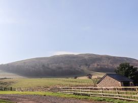 A landscape with a fenced grassy field a stone shed and a hill in the background at Bizzie Lizzie Akeld near Wooler