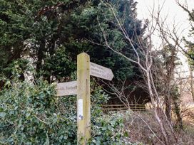 A wooden signpost with directions among trees and bushes at Bizzie Lizzie Akeld near Wooler