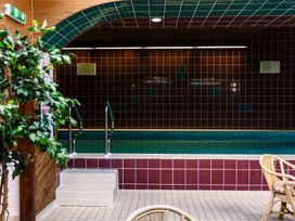 An indoor pool with tiles and a potted plant at Bizzie Lizzie Akeld near Wooler
