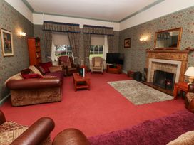 A living room with sofas armchairs a fireplace and a television at Cheviot Manor in Akeld near Wooler