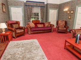 A living room with leather armchairs a sofa a wooden coffee table and floral wallpaper at Cheviot Manor in Akeld near Wooler