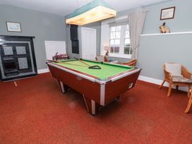 A game room with a pool table two chairs a window and a fireplace at Cheviot Manor in Akeld near Wooler