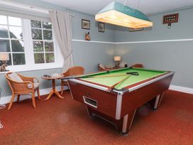 A game room with a pool table chess set and wicker chairs at Cheviot Manor in Akeld near Wooler
