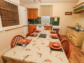 A kitchen with a dining table set for six and an old yellow stove at Cheviot Manor in Akeld near Wooler