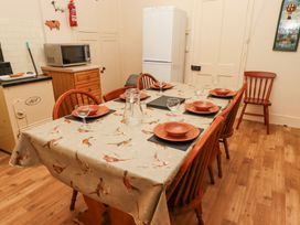 A dining table set with plates glasses and a jug in a kitchen with microwave fridge and wooden chairs at Cheviot Manor in Akeld near Wooler