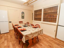 A dining room with a wooden table set for six with plates glasses and a jug between two white refrigerators at Cheviot Manor in Akeld near Wooler