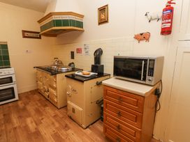 A kitchen with a stove oven range cooker microwave on a wooden cabinet and fire extinguisher on the wall at Cheviot Manor in Akeld near Wooler