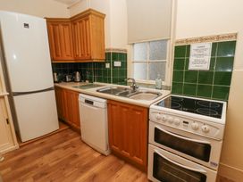 A kitchen with wooden cabinets a refrigerator a dishwasher a double sink and an electric stove at Cheviot Manor in Akeld near Wooler