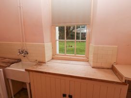 A kitchen sink with taps and wooden countertops below a window showing a grassy yard at Cheviot Manor in Akeld near Wooler