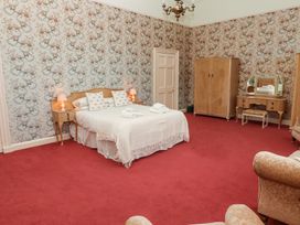 A bedroom with a double bed bedside tables wardrobe dressing table and armchairs at Cheviot Manor in Akeld near Wooler