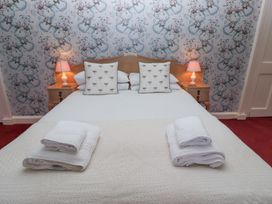 A bedroom with a double bed two bedside tables with lamps and folded towels on the bed at Cheviot Manor in Akeld near Wooler
